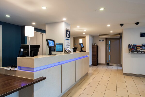 A reception area with a counter, computers, and a blue-lit desk. - Holiday Inn Express Stirling by IHG (Stirling)