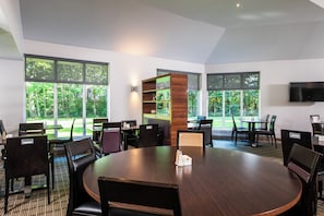 A conference room with a large round table, multiple chairs, and a TV on the wall.