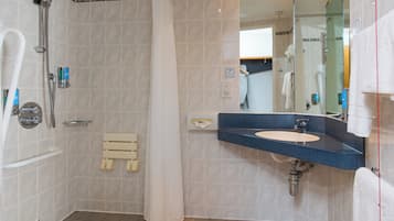 Une salle de bain avec une douche, un lavabo et un miroir.