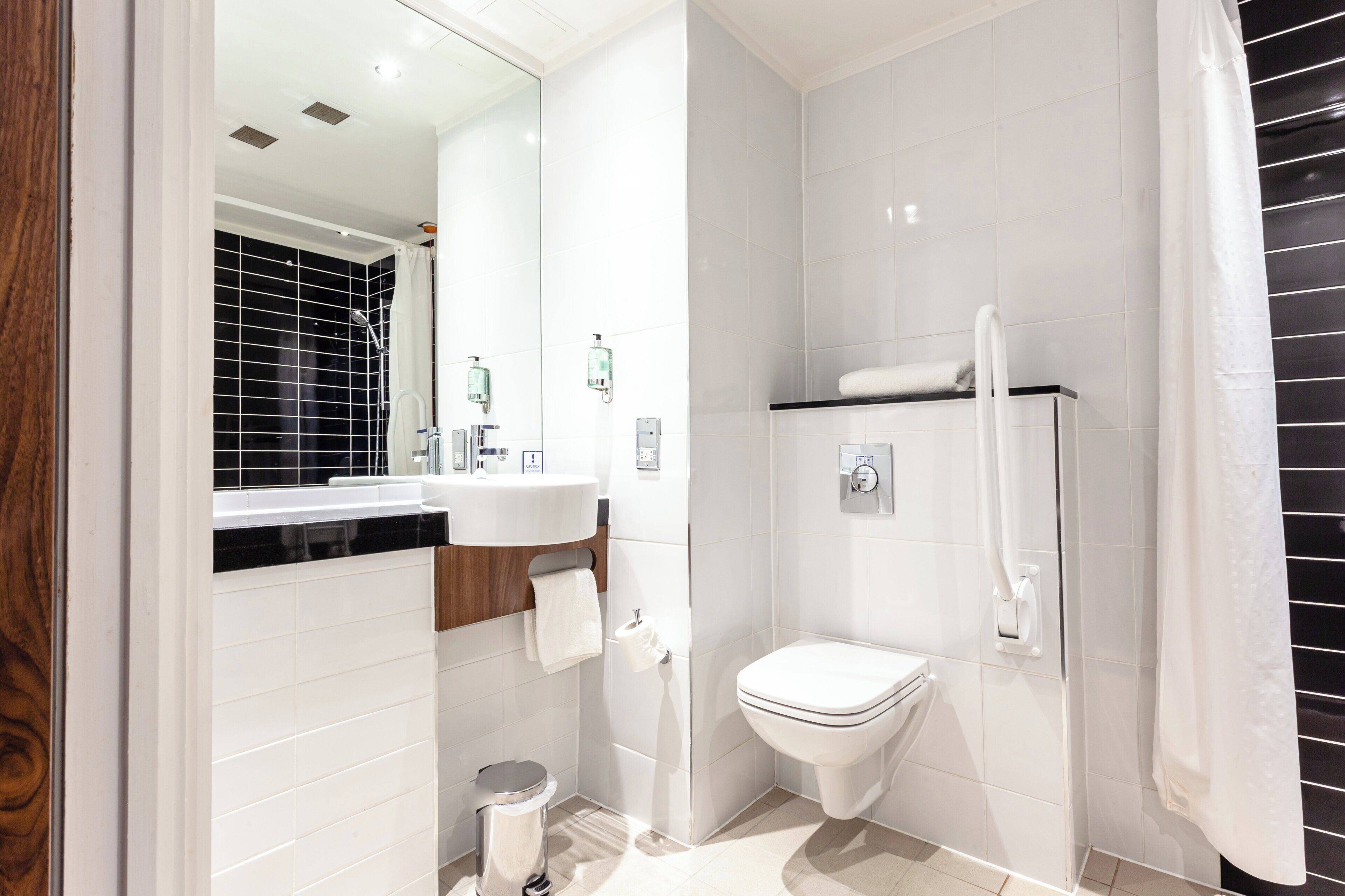 Un baño moderno con lavamanos, inodoro y ducha blancos.