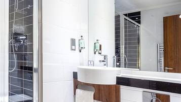 A modern bathroom with a large mirror, a white sink, and a glass shower enclosure.