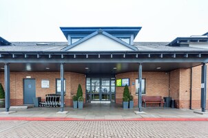 A Holiday Inn Express with a covered entrance, a brick facade, and a parking area with a sign indicating guest parking.