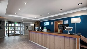 A reception area with a wooden counter, a digital kiosk, and a stone pillar. - Holiday Inn Express Edinburgh Airport by IHG (Newbridge)