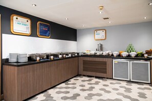 A modern breakfast bar with a black and white color scheme, featuring a refrigerator, a sink, and a variety of breakfast items. - Holiday Inn Express Edinburgh Airport by IHG (Newbridge)