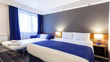 A hotel room with two beds, a large window with blue curtains, a dark textured wall, and two bedside lamps.