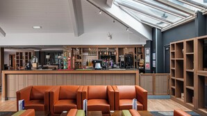A modern bar area with leather seating and a counter stocked with beverages. - Holiday Inn Express Edinburgh Airport by IHG (Newbridge)