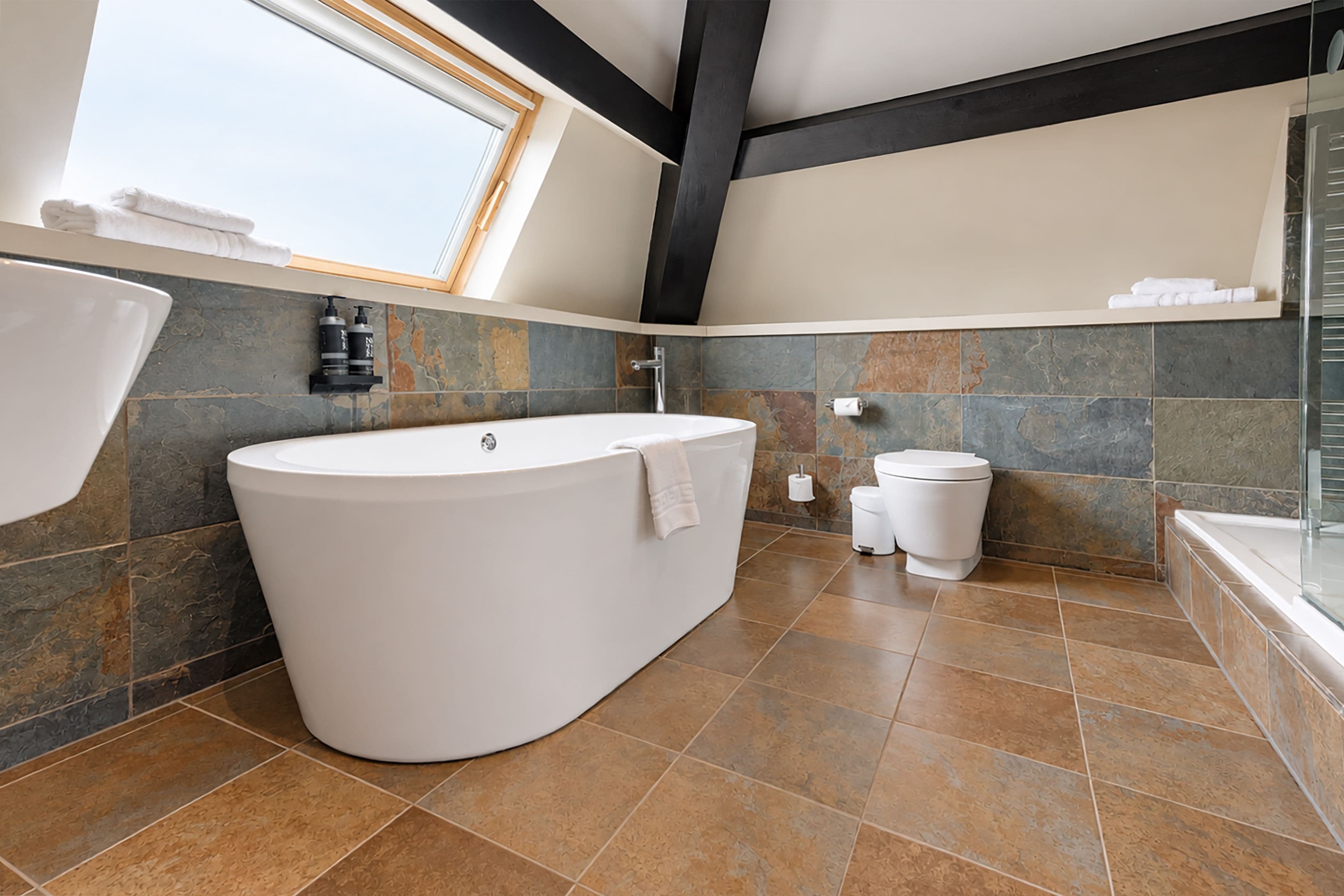 Une salle de bain moderne avec une baignoire sur pieds, des toilettes et un espace douche.