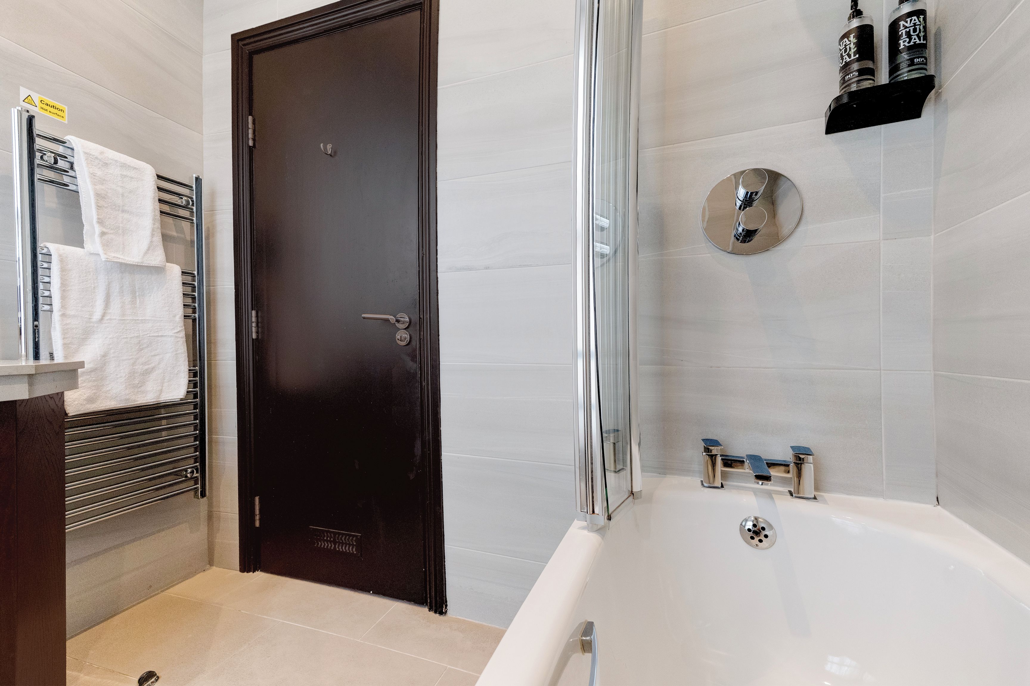 Un baño moderno con bañera, zona de ducha y puerta oscura.
