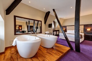 Un baño moderno con dos tinas blancas grandes, un espejo amplio y un mueble de tocador de madera.
