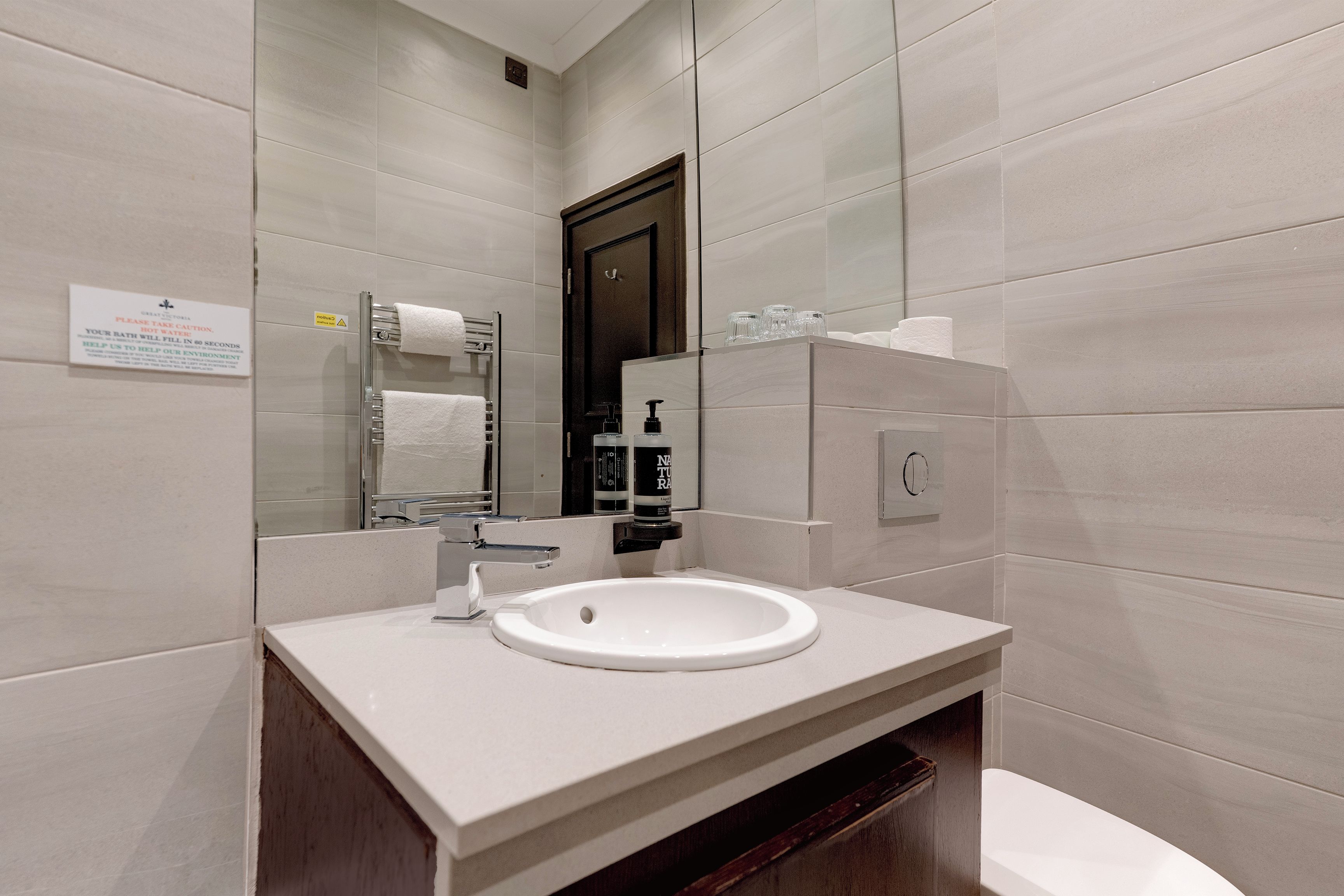 A modern bathroom with a white sink, a mirror, and a towel rack.