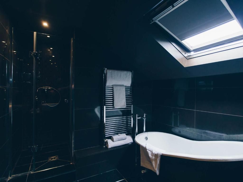 A modern bathroom with a glass-enclosed shower, a freestanding bathtub, and a skylight above the shower.