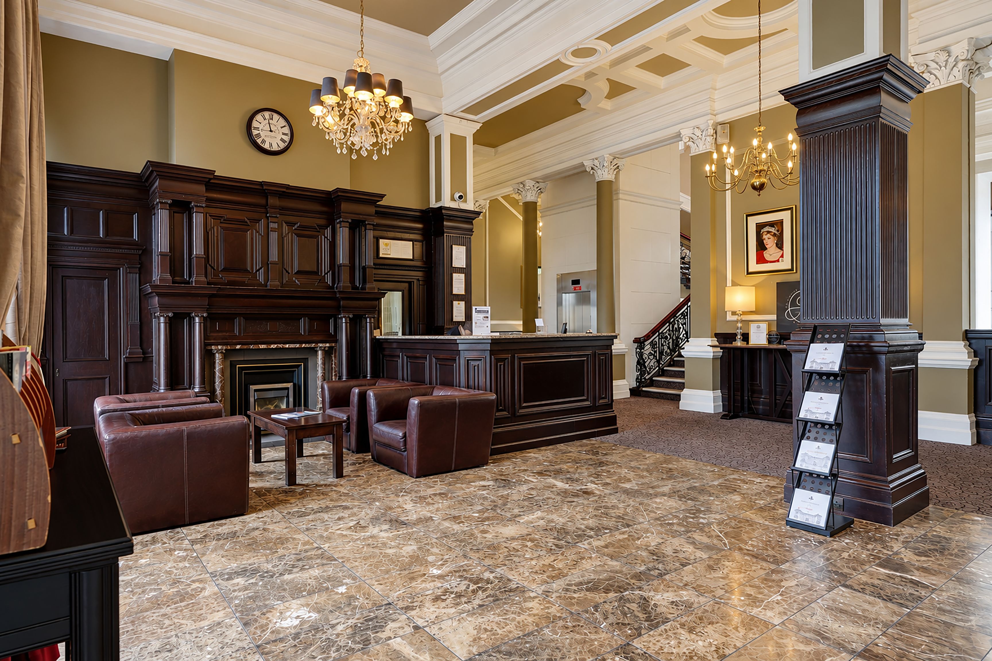 A lobby with a fireplace, leather seating, a reception desk, and a chandelier.
