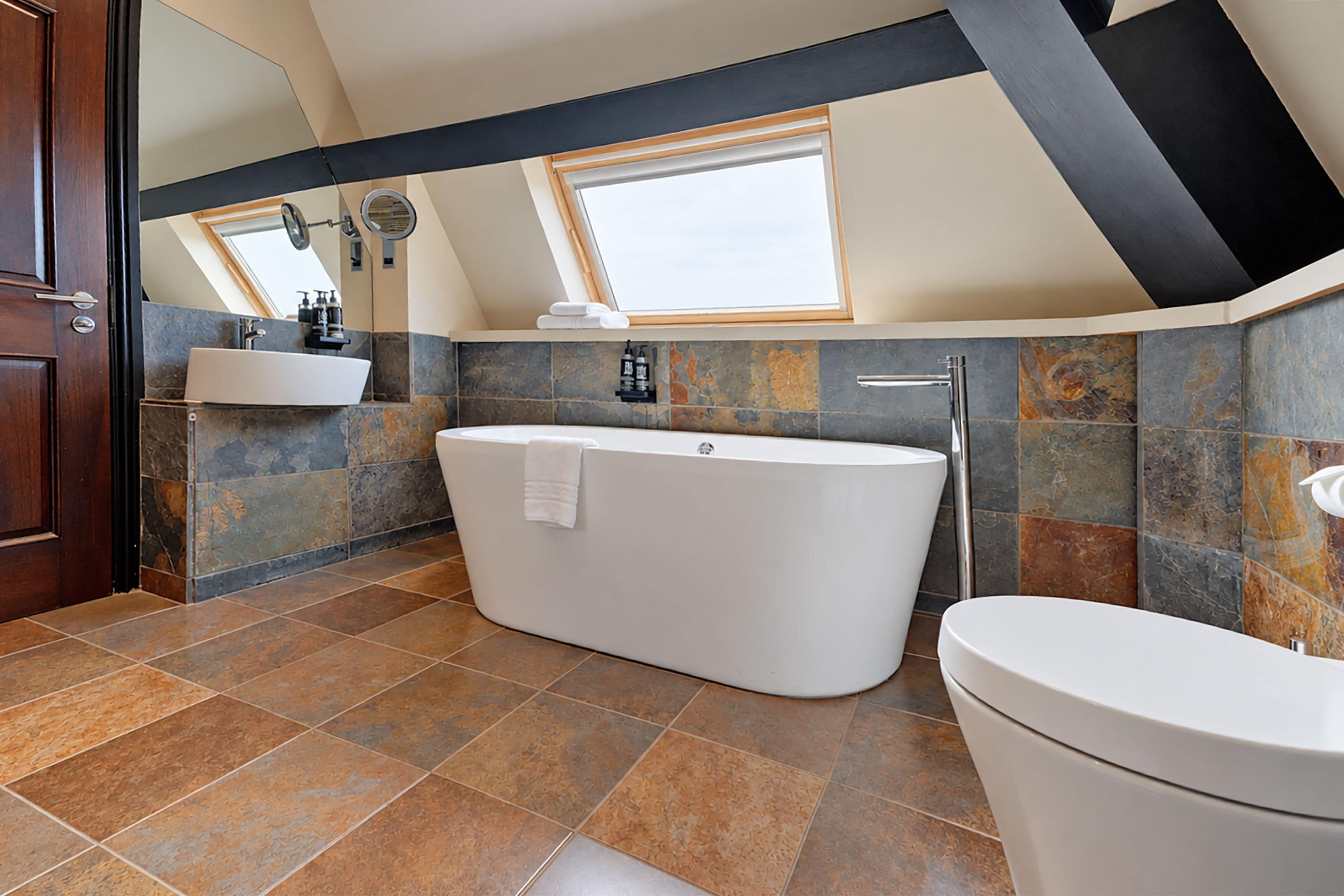 A modern bathroom with a freestanding bathtub, a toilet, and a vanity with a sink.
