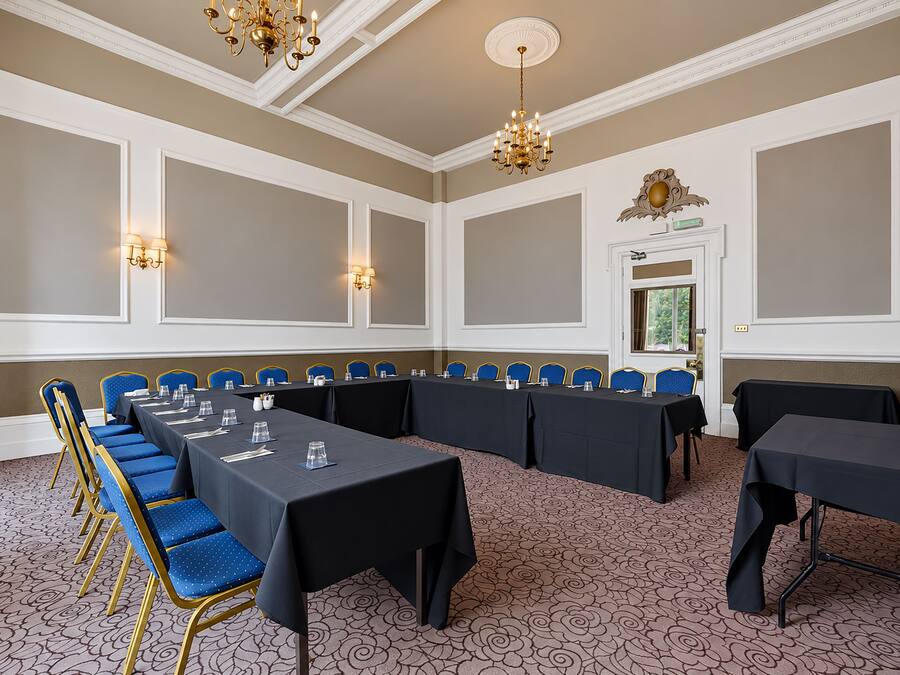 A conference room with a long table, blue chairs, and a patterned carpet.