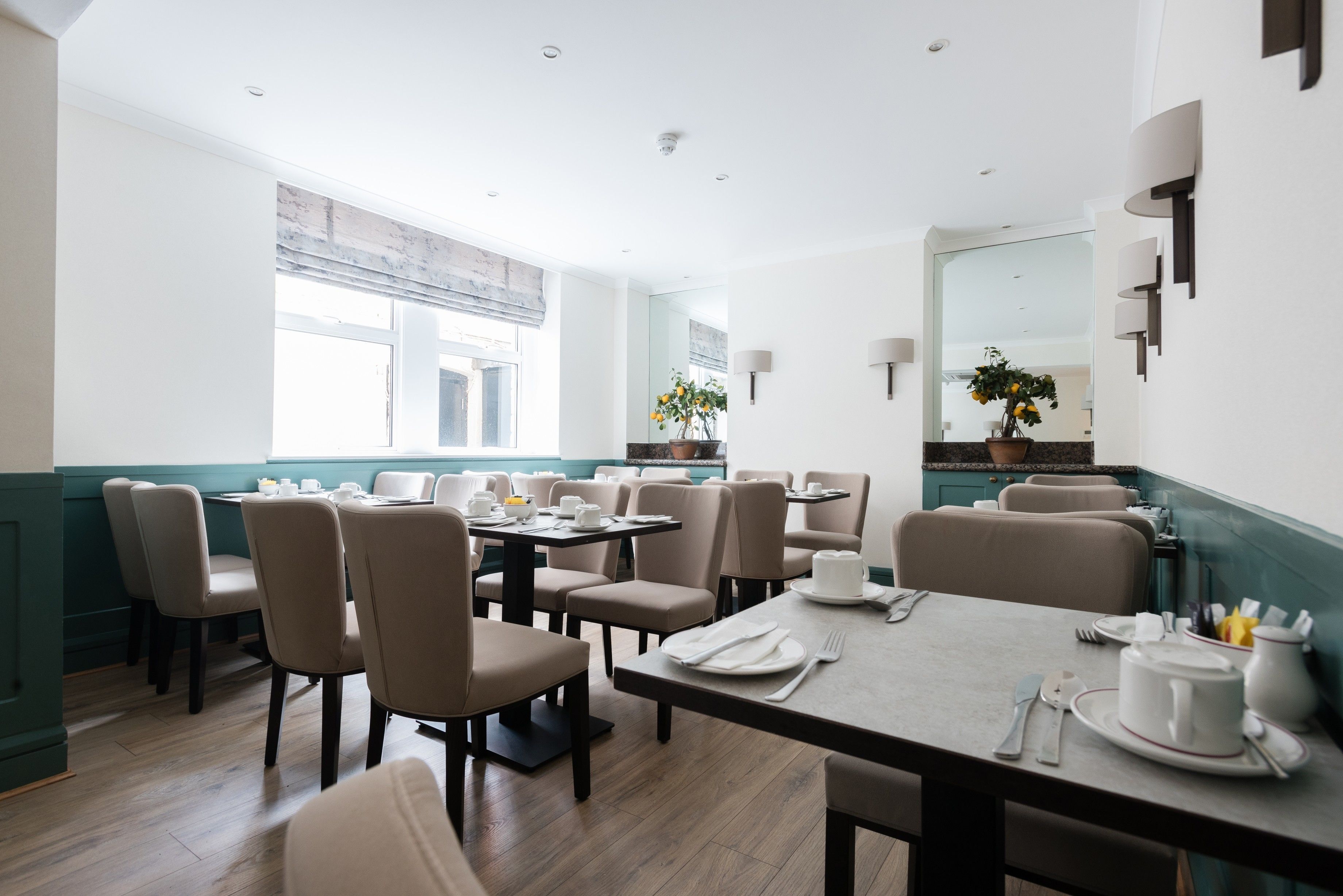 A restaurant with multiple tables and chairs, a large window, and a mirror on the wall.