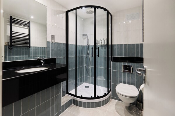 Un baño moderno con ducha de vidrio, lavamanos e inodoro.