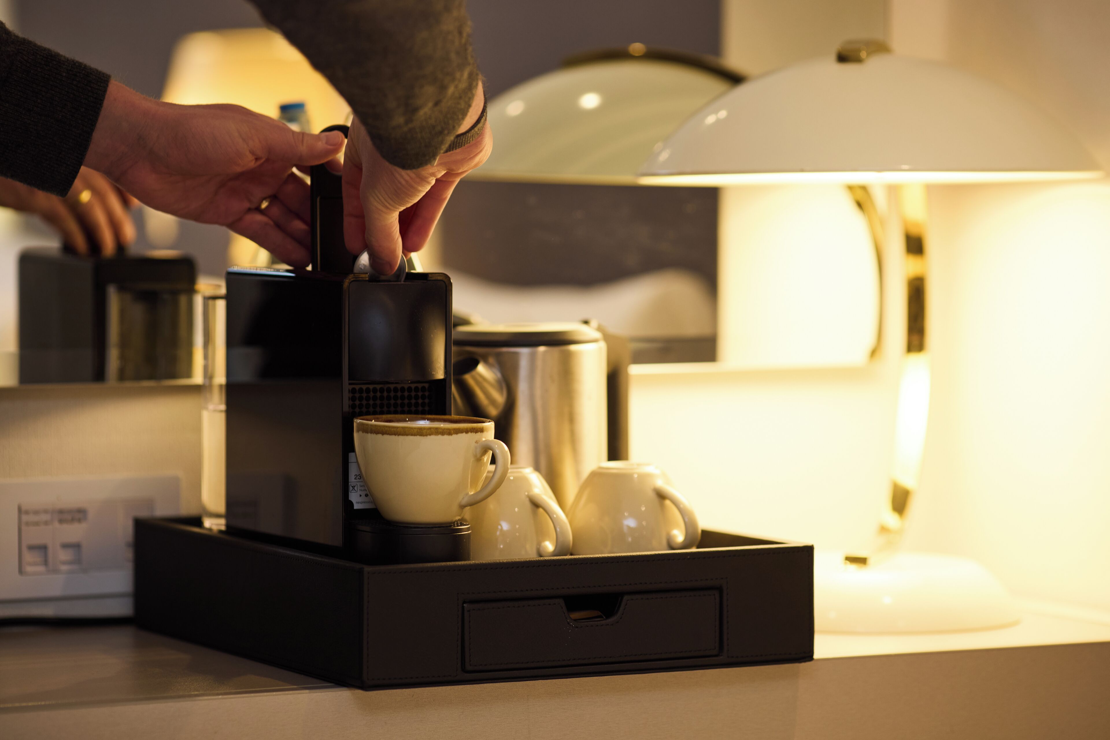 A coffee machine with a tray of cups and a kettle on a countertop.