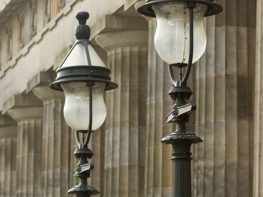 Two street lamps with a classical design, mounted on a pole with a decorative finial at the top.