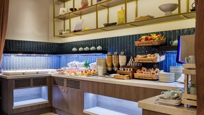 A buffet area with various food items, including fruits, vegetables, and pastries, arranged on shelves and counters. - The Memoir Club (London)
