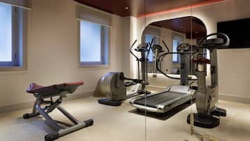 Un gimnasio en casa con cinta de correr, elíptica y máquina de pesas.