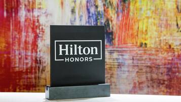A black sign with 'Hilton Honors' text on a white background, placed on a stand.