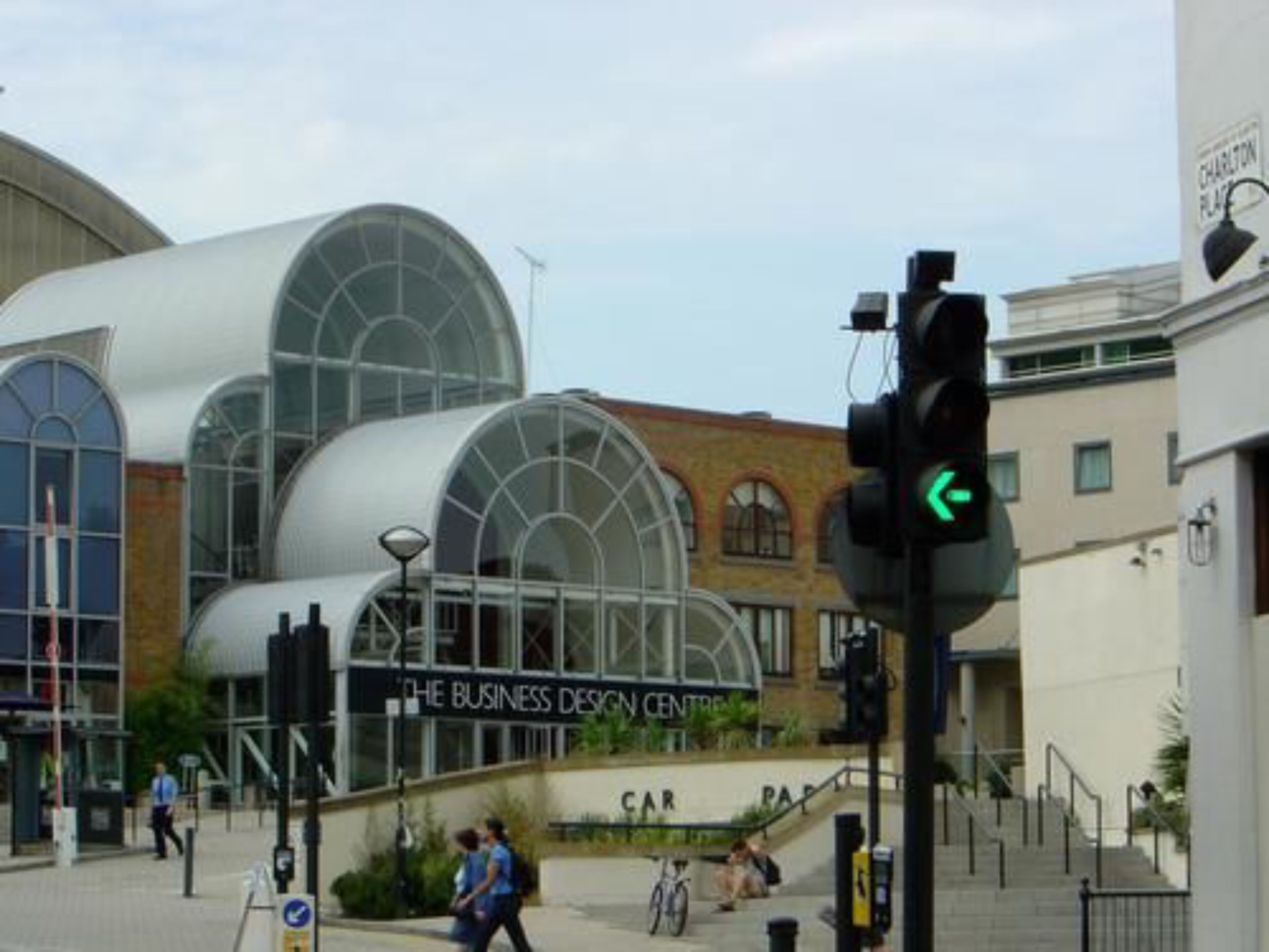 A modern building with large glass windows and a sign for 'The Business Design Centre'.