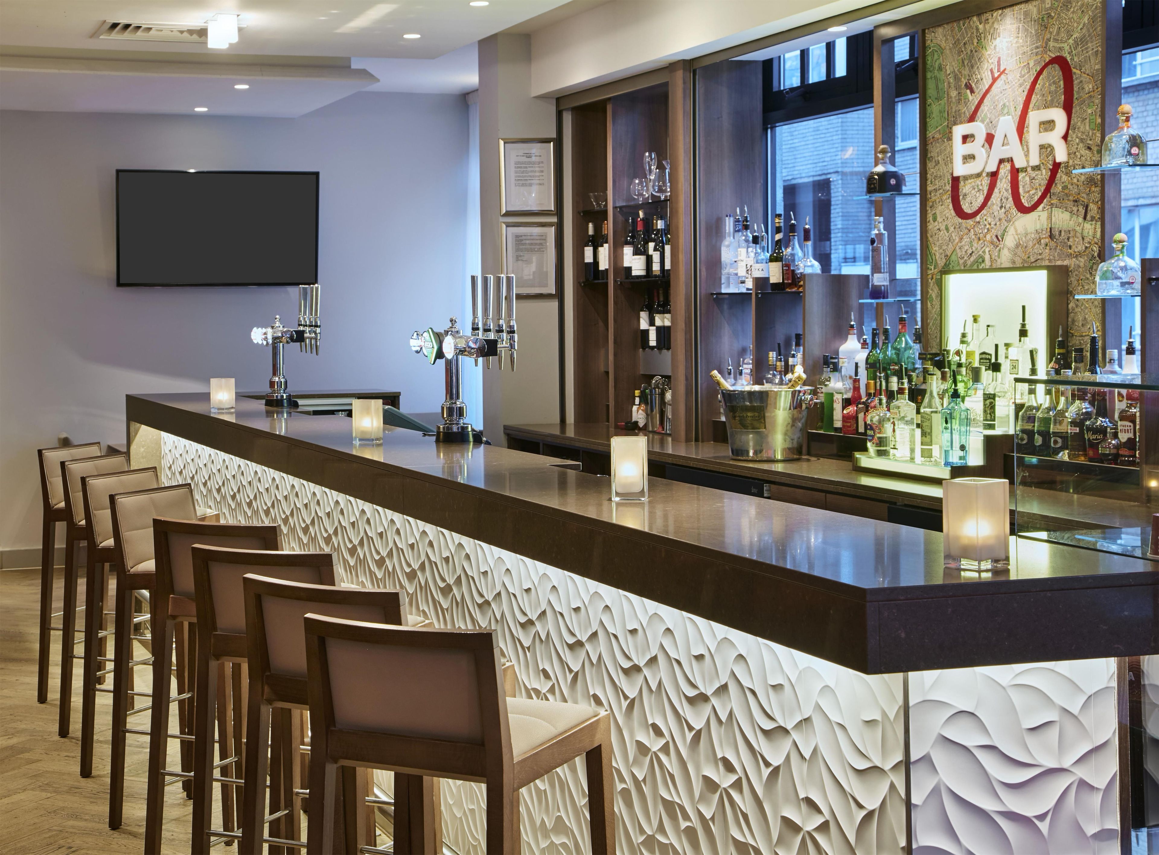 Een bar met een lange toonbank, meerdere tappunten en een divers assortiment flessen.