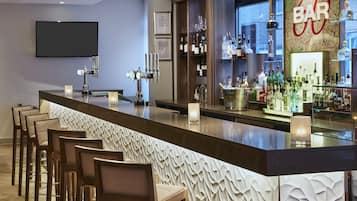 A bar area with a long counter, multiple taps, and a variety of bottles.