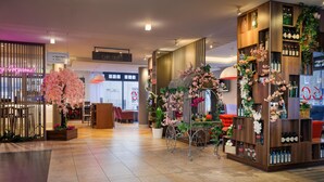 A hotel lobby with a reception desk, a flower cart, and a bar area. - DoubleTree by Hilton London Angel Kings Cross (London)