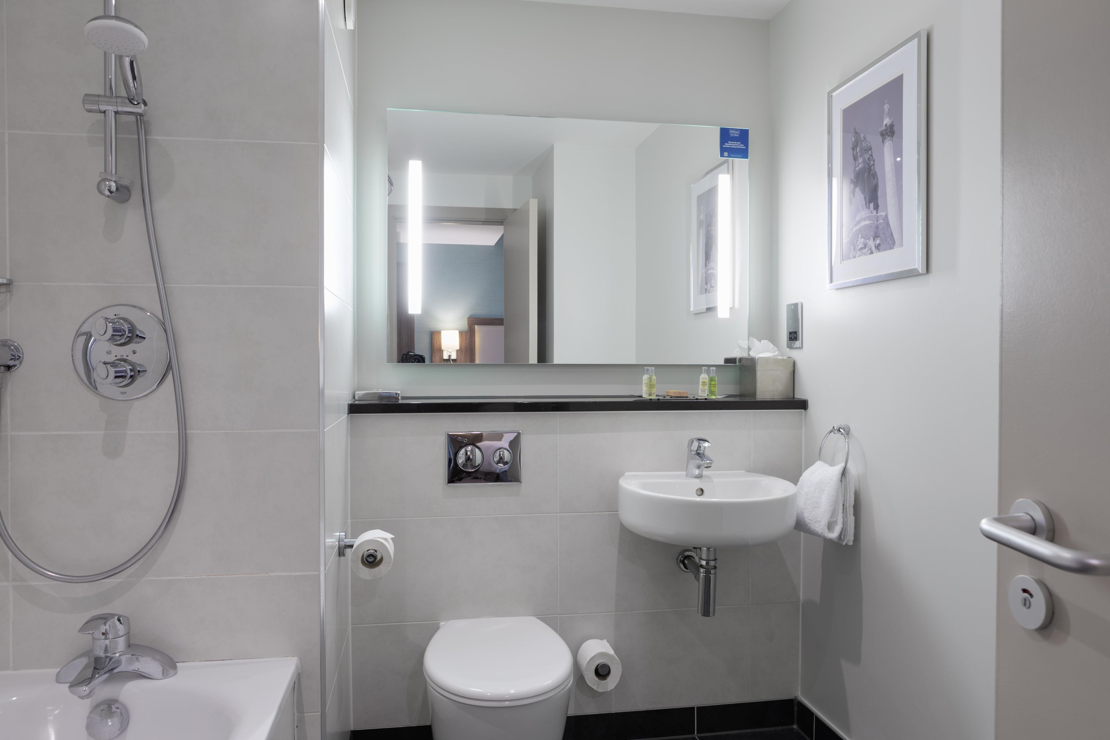 Un baño moderno con ducha, inodoro, lavamanos y espejo.