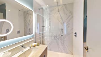 A modern bathroom with a marble shower wall, a large mirror, and a vanity with a sink.