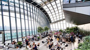 A spacious indoor area with large windows, seating arrangements, and greenery. - DoubleTree by Hilton London Angel Kings Cross (London)