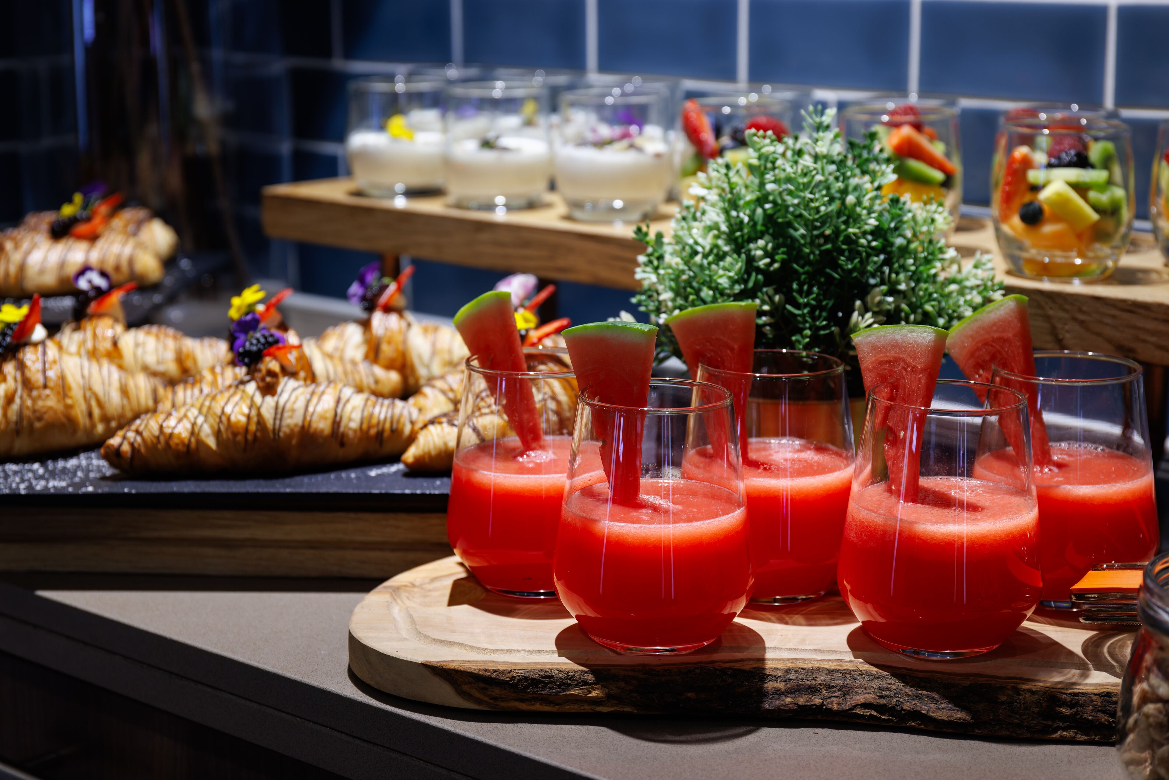 Buffet amb diversos plats i begudes, incloent croissants i amanides de fruita.