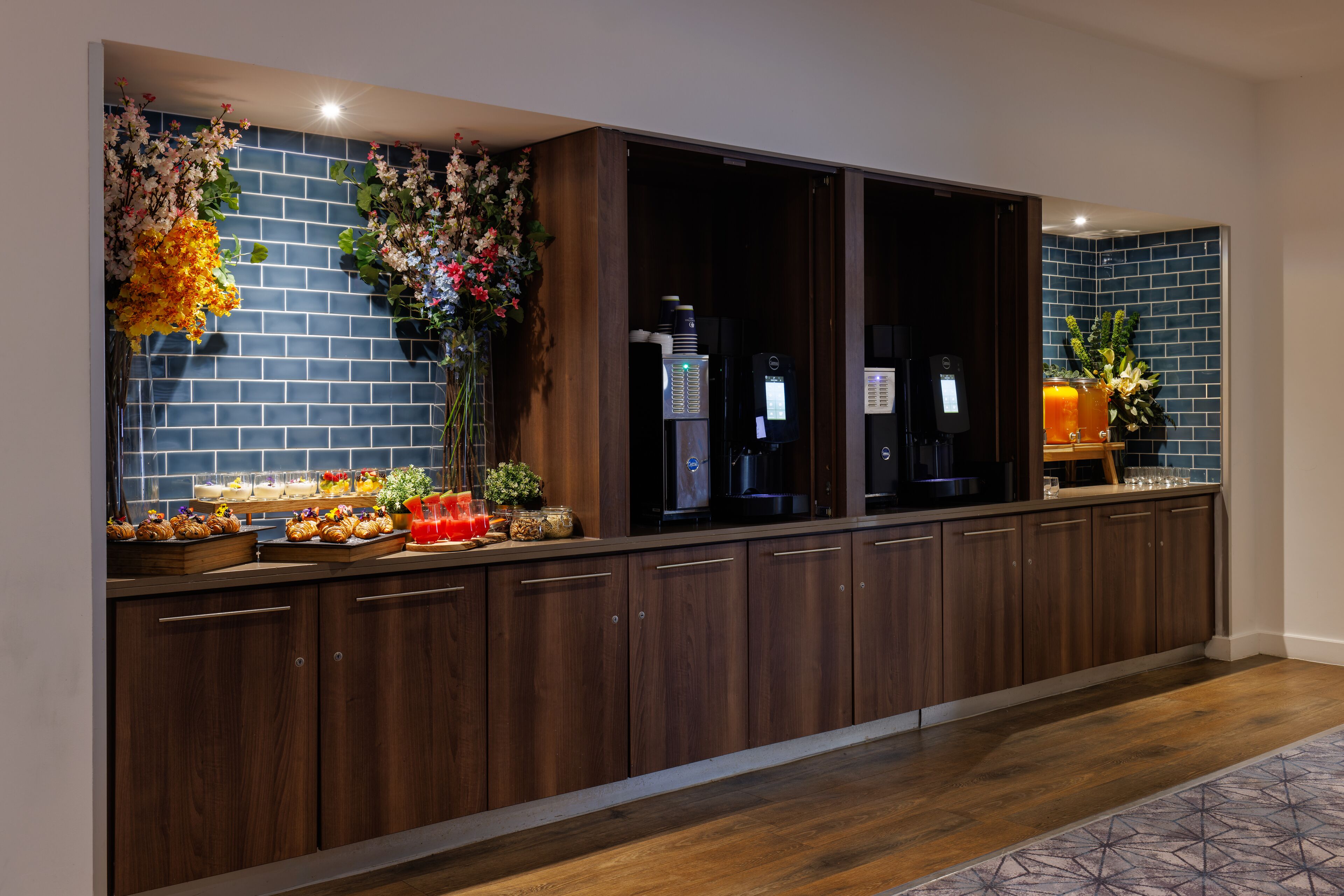 A long kitchen with wooden cabinets, a brick backsplash, and a countertop with various items.