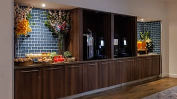 A long kitchen with wooden cabinets, a brick backsplash, and a countertop with various items.