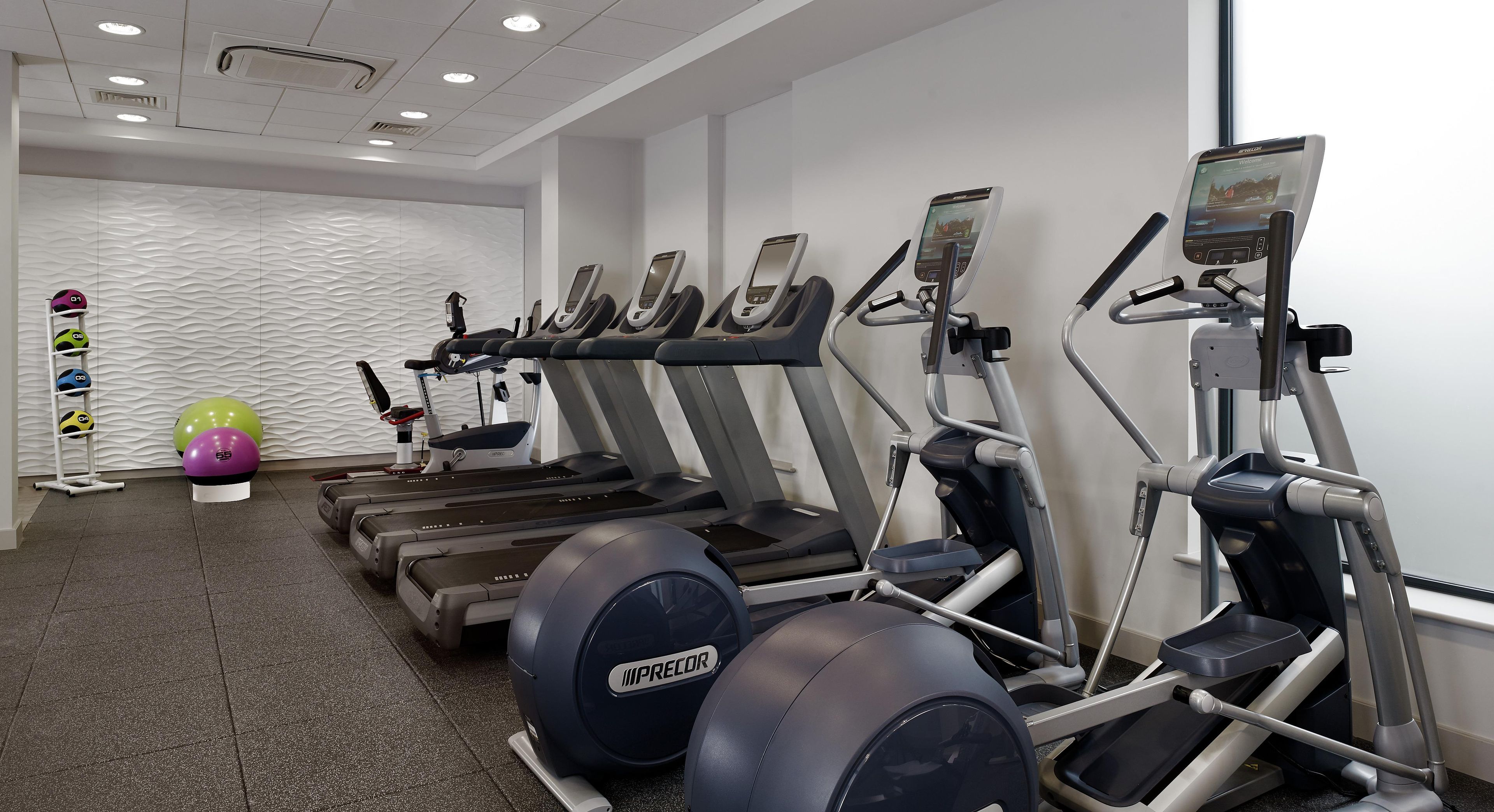 Een fitnessruimte met loopbanden, elliptische trainers en fitnessballen.