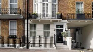 A corner townhouse with a bay window, white trim, and a black metal fence. - Montcalm Mayfair Townhouse (London)