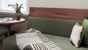A green sofa with a striped throw, a wooden headboard, and a green cushion. - Montcalm Mayfair Townhouse (London)