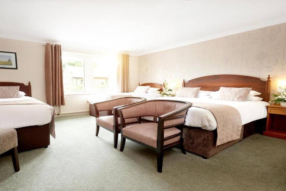 A hotel room with two beds, a chair, and a window with curtains.