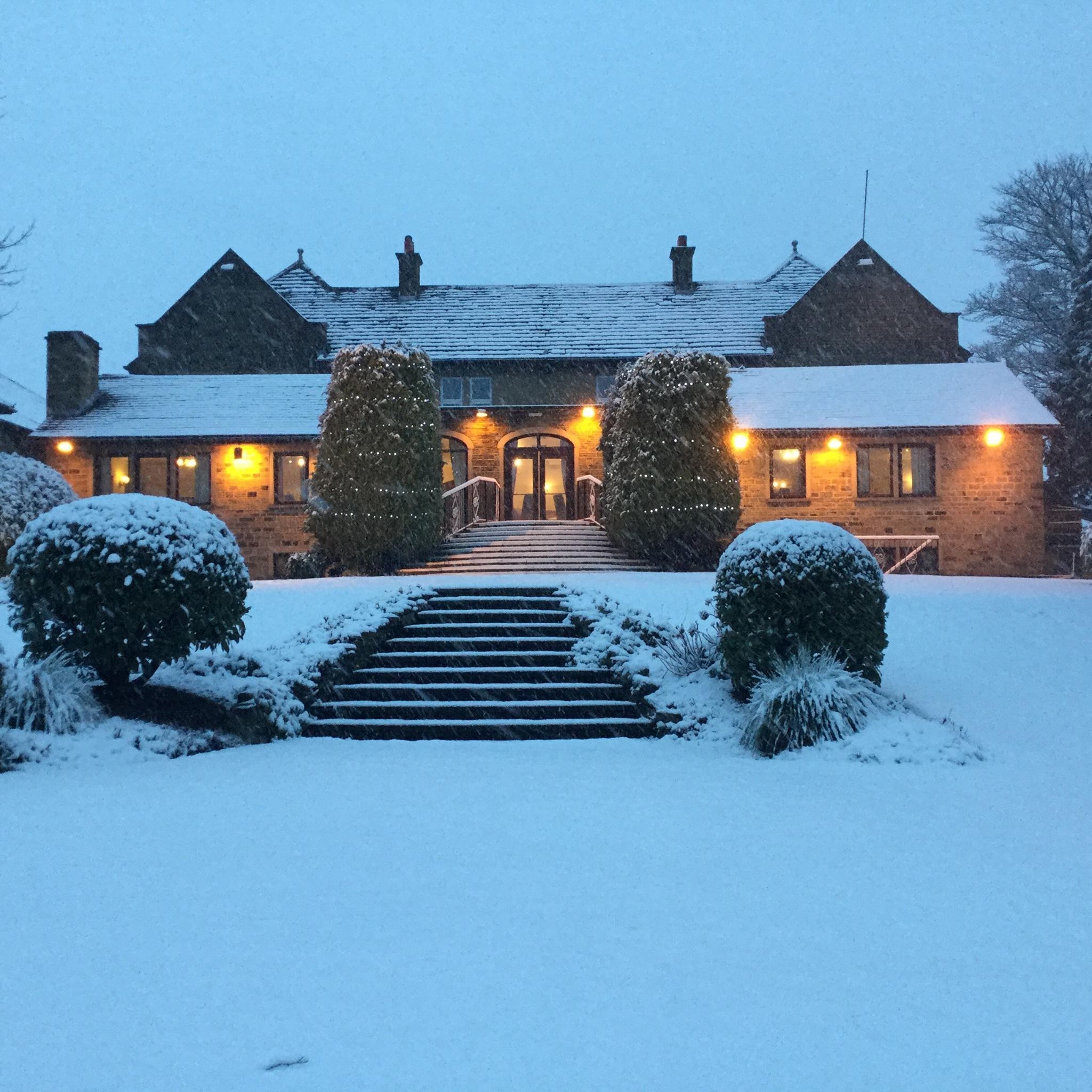 Un edificio cubierto de nieve con una fachada simétrica, una entrada central y una escalera que conduce a las puertas principales.