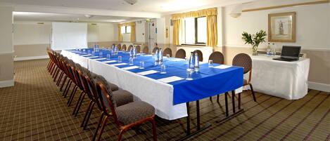 A conference room with a long table, chairs, and a laptop on a table.