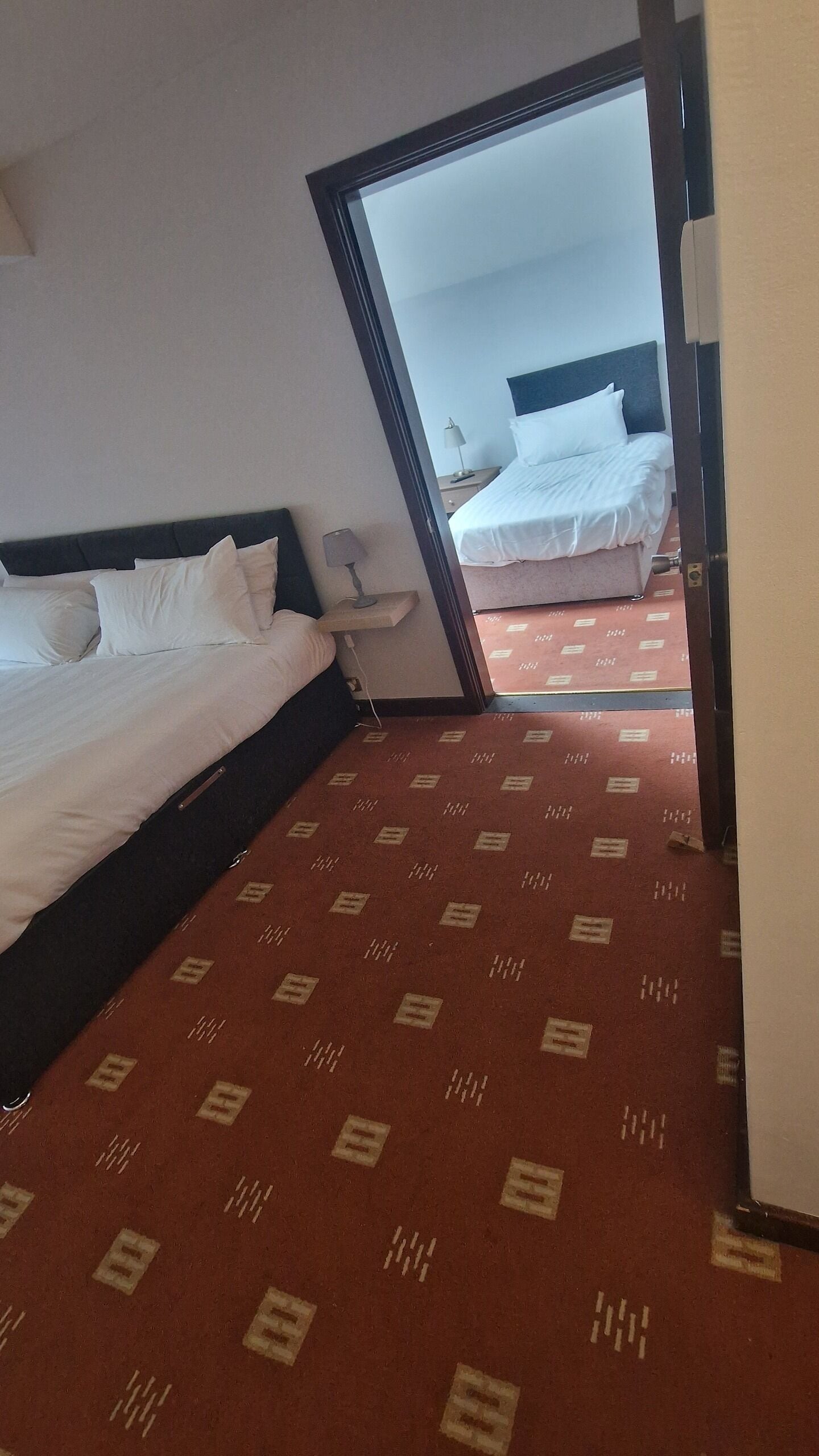 Habitació d'hotel amb un llit gran, un altre més petit i un sòl amb moqueta.