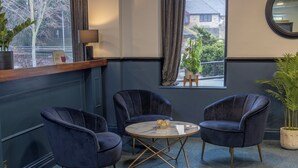 Une pièce avec deux fauteuils bleu foncé, une petite table ronde et une plante en pot.
