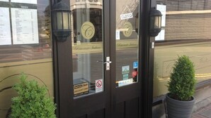 Un restaurant fermé, avec un panneau affichant le menu, une pancarte indiquant « FERMÉ » et une autre pancarte indiquant « BIENVENUE ».