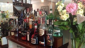 Un comptoir de bar avec différentes bouteilles de spiritueux et un vase de fleurs.