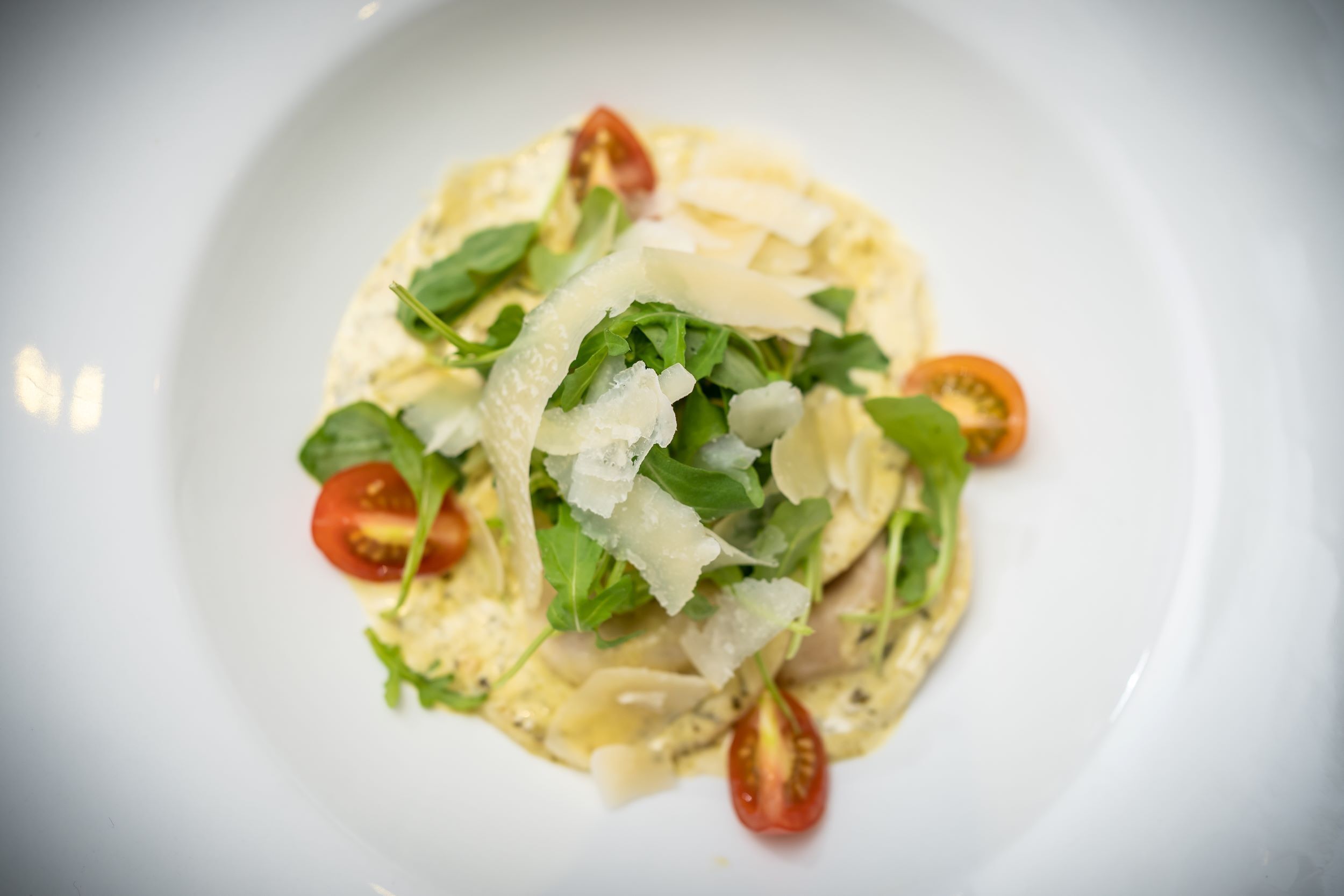 Une assiette de pâtes, de tomates cerises et de fromage.