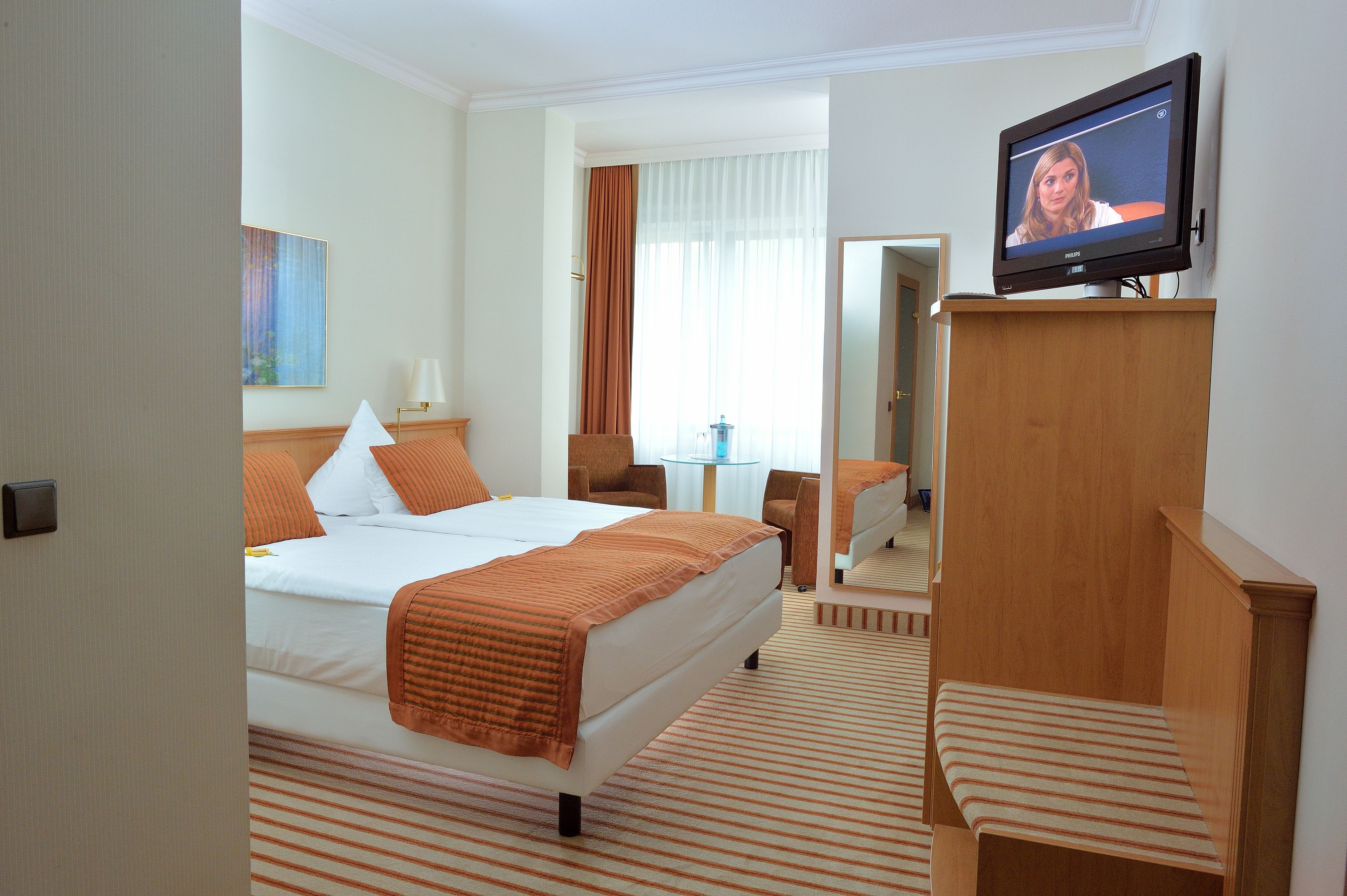 Een hotelkamer met een bed, een televisie, een bureau en een stoel.