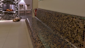 Een modern interieur met een open haard met stenen muur, een mozaïekbank en een kunstwerk met een groene wand.