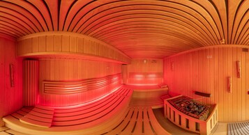 A sauna with curved wooden walls and benches, a wooden bench with a fire, and a small clock on the wall.