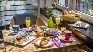 Een ontbijttafel met croissants, fruit en drankjes.